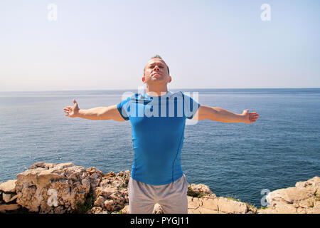 Athletische Passform Runner zu tun stretching Übung, die Vorbereitung für Morgen Workout auf dem Meer. Ein schöner fitness Sportler tun eine Dehnung Routine. Stockfoto