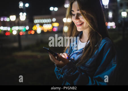 Junge kaukasier Frau sms Handy in der Stadt bei Nacht Stockfoto