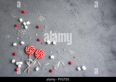 Weihnachten Komposition mit roten und weißen saisonale winter Süßigkeiten, Bonbons und Marshmallows, flach auf Grau legen, kopieren. Weihnachten Grußkarte, desi Stockfoto