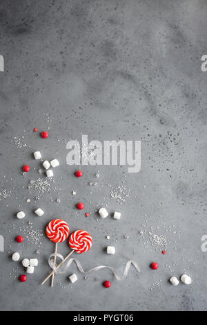 Weihnachten Komposition mit roten und weißen saisonale winter Süßigkeiten, Bonbons und Marshmallows, flach auf Grau legen, kopieren. Weihnachten Grußkarte, desi Stockfoto