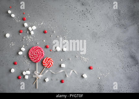 Weihnachten Komposition mit roten und weißen saisonale winter Süßigkeiten, Bonbons und Marshmallows, flach auf Grau legen, kopieren. Weihnachten Grußkarte, desi Stockfoto