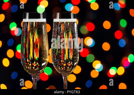 Zwei Gläser Champagner auf schwarzem Hintergrund mit farbigen Leuchten Stockfoto