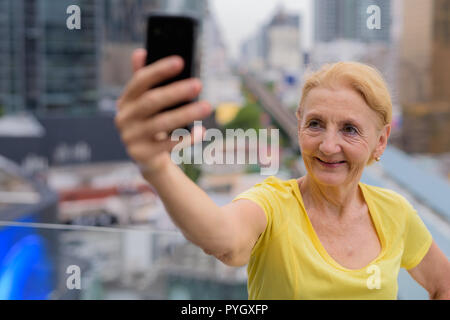 Schöne ältere Frau unter selfie mit Handy in Stadt Stockfoto