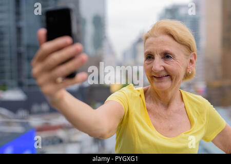 Schöne ältere Frau unter selfie mit Handy in Stadt Stockfoto