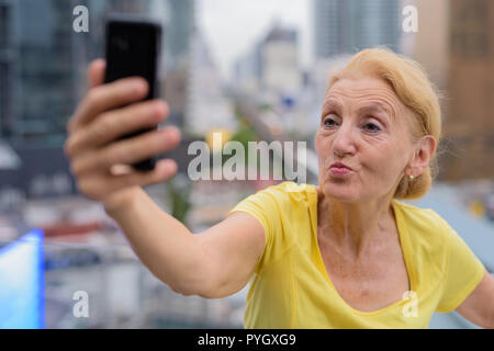 Schöne ältere Frau unter selfie mit Handy in Stadt Stockfoto