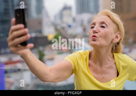 Schöne ältere Frau unter selfie mit Handy in Stadt Stockfoto