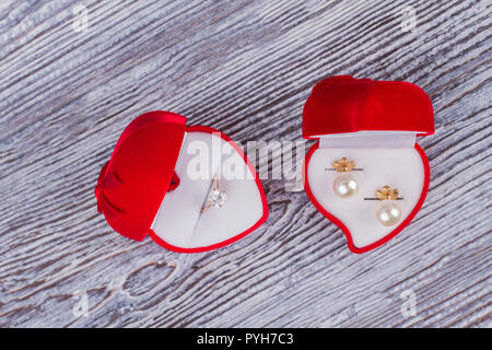 Red velvet Geschenkboxen mit Schmuck. Hochzeit Ring Box und Box mit Perle Ohrringe auf Holz- Hintergrund. Romantisches Geschenk Konzept. Stockfoto