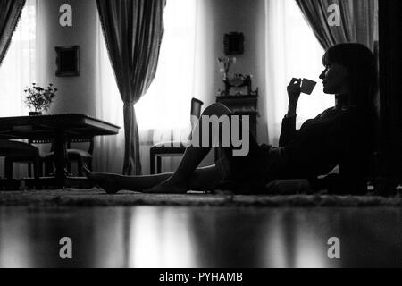 Friedliche Frau mit Tasse Tee zu Hause entspannen Stockfoto