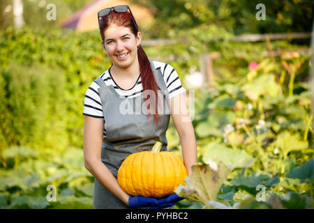 Portrait von Frau mit Kürbis in die Hände am Garten im Sommer Tag. verschwommenen Hintergrund. Stockfoto