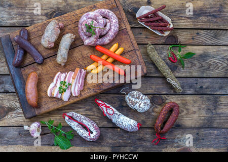 Auswahl an französischen Raw Charcuterie Bord, mit Rucola Blätter und trockene Wurst über eine Holz- Hintergrund Stockfoto