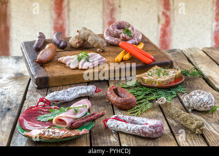 Auswahl an französischen Raw Charcuterie Bord, mit Rucola Blätter und trockene Wurst über alten roten Fachwerkhaus Wand Hintergrund. Stockfoto