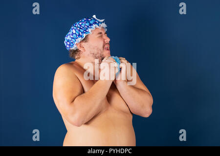 Funny fat man in blaue Kappe und mit Schwamm in der Dusche Stockfoto