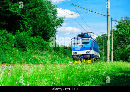 Eine blaue elektrische Lokomotive der tschechischen Landschaft. Ein Zug durch das grüne Tal. Schienenverkehr in der Tschechischen Republik Stockfoto