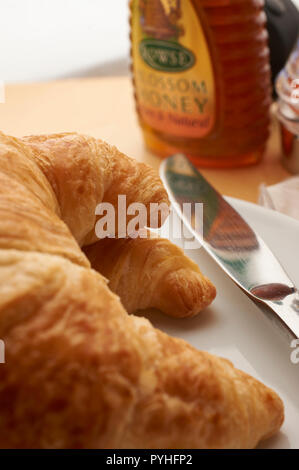 Kontinentales Frühstück mit frischen Croissants und Honig, auf weissem leinen Tischdecke Stockfoto