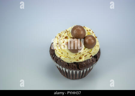 Essen Thema, Ansicht von isolierten und leckeren weißen und schwarzen Cupcake mit Späne von Schokolade und Kugeln oben, weißer Hintergrund Stockfoto