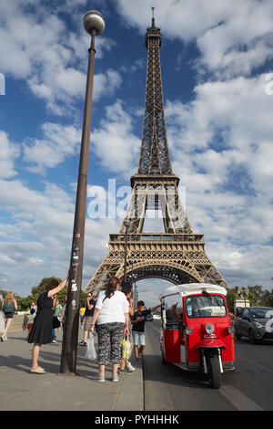 Paris, Ile-de-France, Frankreich - Touristen in einer autorikscha auf der Pont d'Iéna Brücke, im Hintergrund der Eiffelturm - das Wahrzeichen der französischen Hauptstadt. Stockfoto