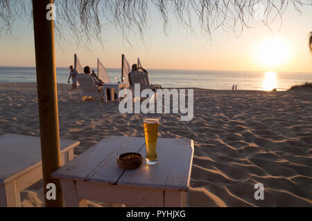 Kaltes Bier in der heißen Abendsonne auf einem portugiesischen Strand bei Sonnenuntergang. Stockfoto