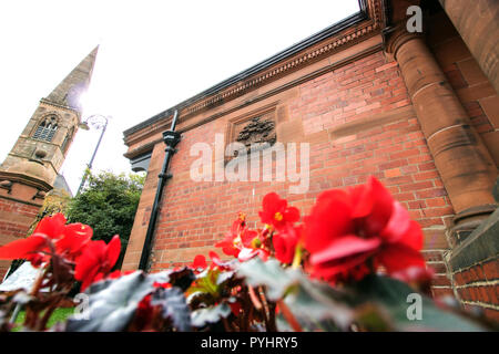 Blüten vor eine illustrierte Detail der Glasgow Motto, "Lassen Sie Glasgow Gedeihen", auf einem Backsteinbau, botanischen Gärten, Glasgow, Schottland Stockfoto