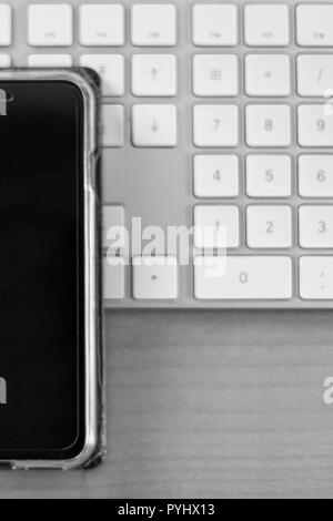 Monochrome Nahaufnahme von einem Smartphone liegen auf einem weißen Tastatur, Desktop Stockfoto