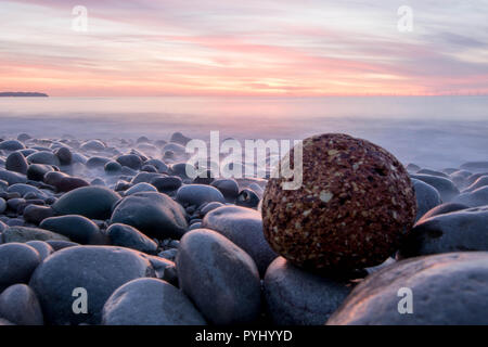 Red Rock auf weißem Kies Sunset Beach - North Wales Stockfoto