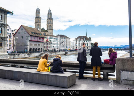 Zürich, Schweiz - März 2017: Junge Studenten Menschen genießen den Blick auf den Fluss Limmat und Grossmünster am Rathaus Brücke Rathausbrücke, Stockfoto