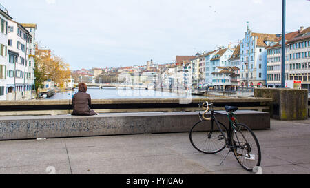 Zürich, Schweiz - März 2017: Frau mit Fahrrad genießen Sie den Blick auf den Fluss Limmat und Zürich Riverside am Rathaus Brücke Rathausbrücke, Zürich Stockfoto