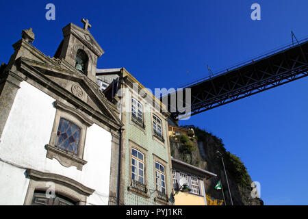 Einzelheiten über die interessante und vielfältige Architektur von Porto zu sehen, einer der berühmten und allgegenwärtigen Brücken über die Häuser, gegen seine Deep Blue sk Stockfoto