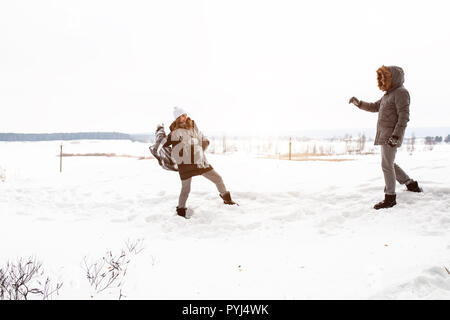 Sorglos glückliches junges Paar gemeinsam Spaß im Schnee im Winter woodland das Werfen mit Schneebällen an jedem anderen während eines mock kämpfen. Stockfoto