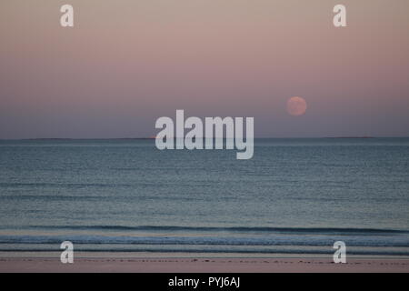 Der Mond steigt in einem purple haze schwebt über den Ozean. Stockfoto