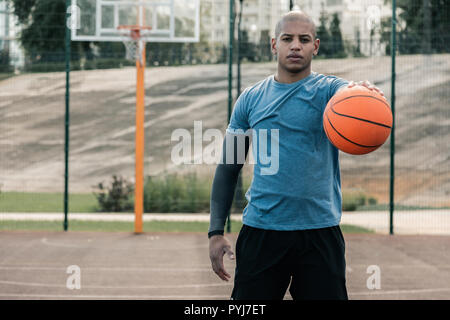 Stattliche gut Mann stand auf dem Basketballplatz gebaut Stockfoto