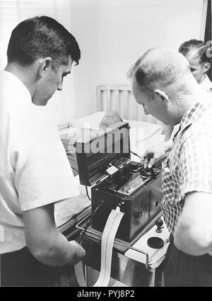 (1961) - - - Astronaut John Glenn Jr. in einem elektrokardiographen von Dr. Jackson während der medizinischen Prüfung im Pensacola Naval Station gemacht. Stockfoto