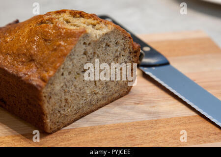Selbstgemachte Banane Brotlaib auf eine Küche Schneidebrett mit Messer Stockfoto