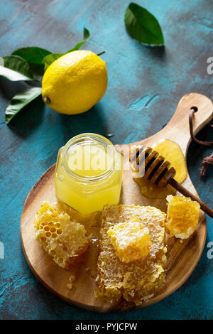 Natürlicher Honig mit Zitrone. Honig im Glas und Pendelarm, Süße Waben auf blauen Tisch aus Stein. Stockfoto