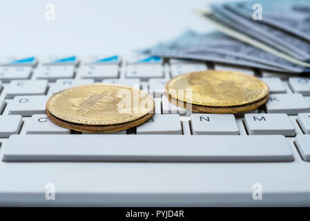 Bitcoin Münze mit Tastatur und US-Dollar. Bitcoin Goldmünzen auf Dollar Banknoten Büro mit einem weißen Hintergrund. Digitale cryptocurrency. Münzen Stockfoto