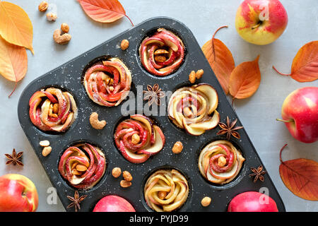 Fach von Apple Rosen in Blätterteig gebacken auf grauem Beton Hintergrund mit Herbstlaub und rote Äpfel Stockfoto