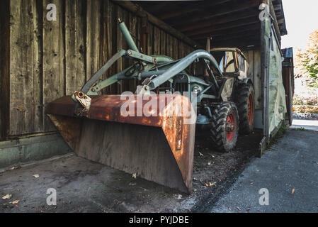 Alte türkisfarbenen Eicher Traktor mit Hubarm und rostigen Schaufel in einem dunklen Schuppen, Bayern, Deutschland Stockfoto