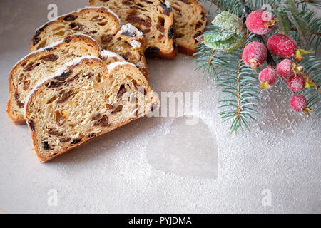 Christstollen auf Licht Steintafel mit Tannen Zweigen und Frosted berriy Dekorationen. Traditionelle deutsche Dessert für Weihnachten feiern. Stockfoto