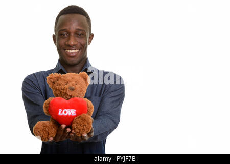 Junge glücklich afrikanischer Mann lächelnd und Teddybär mit Herz Stockfoto