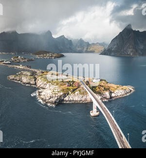 Antenne Panoramablick auf Reine traditionelle Fischerdorf in der Lofoten Inseln im nördlichen Norwegen mit blauem Meer und Berge während der sonnigen arcti Stockfoto