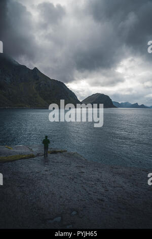 Einsamer Mann, der vor den Atlantischen Ozean und auf die stürmische See. Silhouette der Meereslandschaft mit allein der Mensch auf den Felsen bei Sonnenuntergang Himmel. Ph Stockfoto