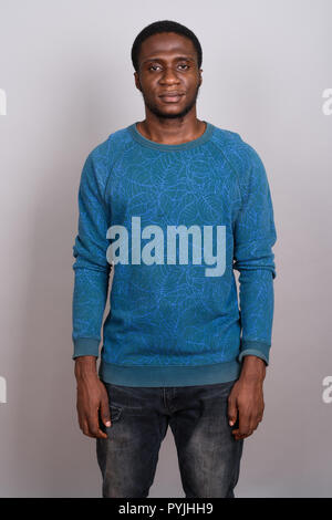 Junge afrikanische Mann trägt blaue Langarm Shirt gegen Grau b Stockfoto