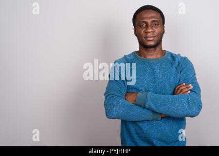Junge afrikanische Mann trägt blaue Langarm Shirt gegen Grau b Stockfoto