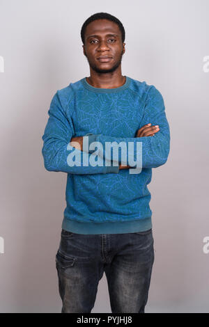 Junge afrikanische Mann trägt blaue Langarm Shirt gegen Grau b Stockfoto