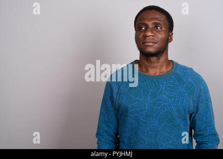 Junge afrikanische Mann trägt blaue Langarm Shirt gegen Grau b Stockfoto