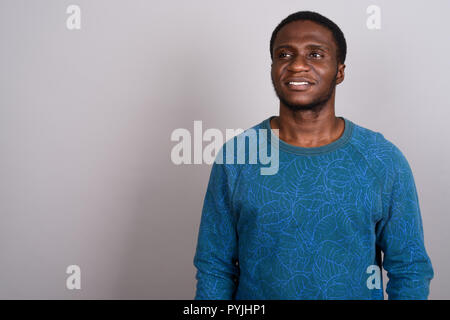 Junge afrikanische Mann trägt blaue Langarm Shirt gegen Grau b Stockfoto