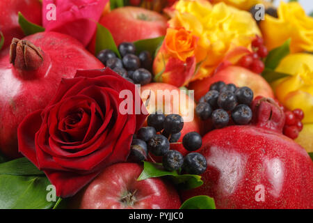 Noch immer leben bestehend aus Granatäpfel, Äpfel, schwarze Eberesche, rot Viburnum, Birnen, Zitronen und Blumen der rote und gelbe Rosen close-up Stockfoto