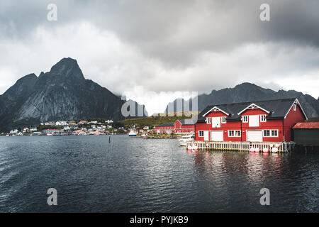 Landschaft von Fischerdorf Reine mit der Reine Fjord bei Sonnenuntergang mit schönen Lichter auf Berge, blauer Himmel und Wolken. Lofoten, Norwegen. Foto Stockfoto