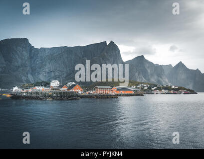 Gelbe rorbu Häuser von Sakrisoy Fischerdorf an einem bewölkten Tag mit Bergen im Hintergrund. Lofoten, Norwegen. Foto in Norwegen übernommen. Stockfoto