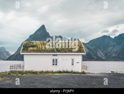 Lofoten norwegen - September 2018: Haus mit Grasdach und die Berge im Hintergrund an einem bewölkten Tag. Lofoten ist ein Archipel Stockfoto