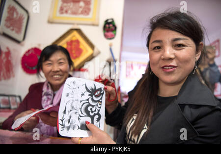 (181029) - Yan'an, Oktober 29, 2018 (Xinhua) - Wang Yaya (R) und Yao Jianzhen Papier erlernen - Schneiden an eine Gemeinschaft Workshop in Ansai Huaziping County im Bezirk, Yan'an, Provinz Shaanxi im Nordwesten Chinas, Okt. 19, 2018. Ansai Bezirk, im nördlichen Teil der Provinz Shaanxi auf dem Löß-Plateau, ist bekannt für seine einzigartige Volkskunst wie Ansai Taille Drum Dance bekannt, Papier-cut, Volkslieder, volkstümliche Malerei und Oper. In den letzten Jahren, Ansai hat sich bemüht, den kulturellen Tourismus durch die Integration von Tourismus mit diesen einzigartigen Volkskunst, um der Armut zu fördern. Nach einer Schulung, pe Stockfoto